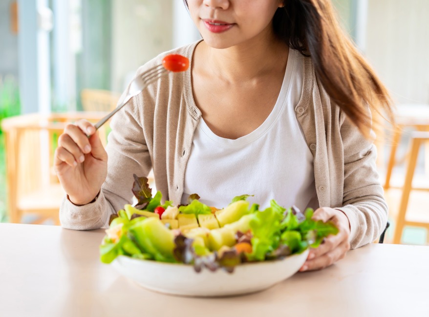 Fotografía de una mujer comiendo una ensalada 