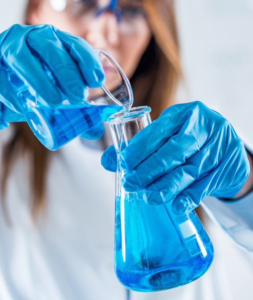 Imagen mujer revolviendo líquidos en frascos de laboratorio